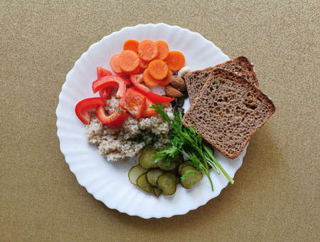 Barley groats with red pepper, carrots, pickled cucumber, wholemeal bread, parsley and nutsの写真素材