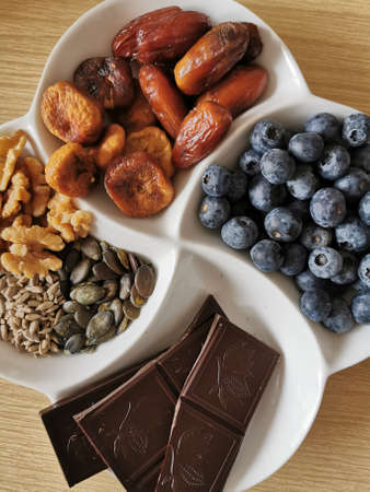 A healthy sweet snack. Chocolate, nuts, pumpkin seeds, sunflower seeds, blueberries, dried figs,...