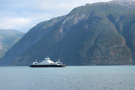 A ferry is floating across fjord.の写真素材