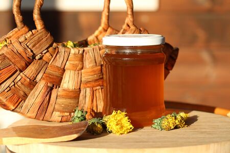 Jam of dandelions in the jar and dandelion flowers in wooden basketの写真素材