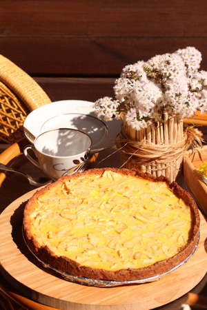 Tea party on sunny patio chatting. Apple Tart and vase of flowers on the table. Summer time on the...