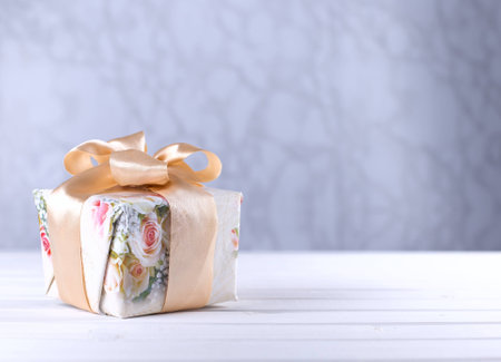 Floral pattern gift box tied with ribbon on wooden table with copy space mother`s dayの写真素材
