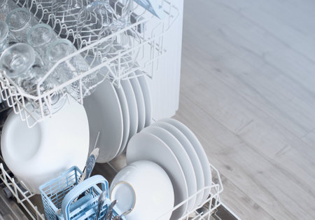Open dishwasher with clean utensils in itの写真素材