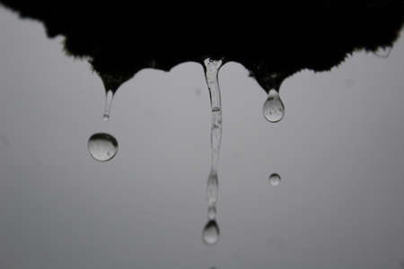 Drops falling down from the roof black background texture