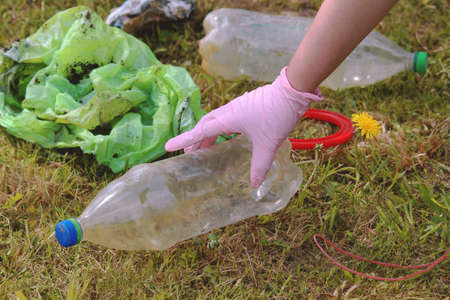Saving the planet earth from pollution of plastic. Dandelion sprout and bottle on the green grass....