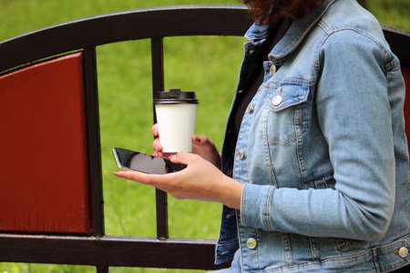 business woman girl student with the nude manicure holding phone screen menu and cup of coffee...