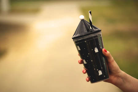 woman hand girl student holding eco friendly cup of coffee or herbal tea with the school bag in the...