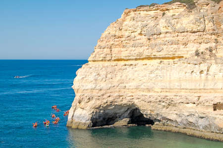 Rock formations and people doing kayaks in the Atlantic ocean to visit the Benagil caves, Algarve, Portugalの写真素材