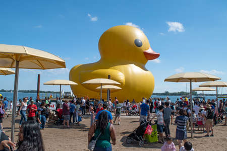 Toronto, Canada - July 2, 2017: Yellow giant rubber inflatable duck in the waterfront in Toronto with yellow umbrellas and the island in the background in the 150 anniversary of Canadaのeditorial素材