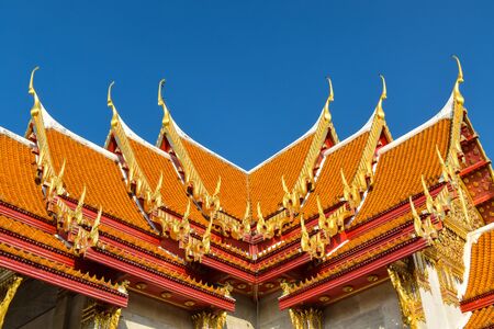 Details of typical Thai traditional roof with ceramic tiles and golden ornamentationの写真素材