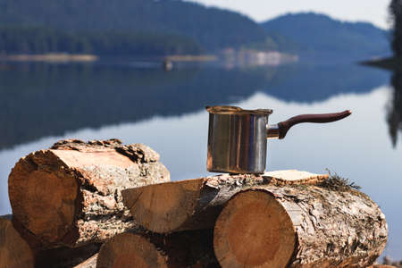 Coffee can on chopped wood with the blurred Beglika dam on the background. The photograph was taken...
