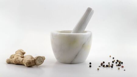 Marble mortar composition with ginger root and white, red and black pepper isolated on a white...