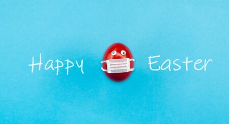 Easter red egg with a medical mouth mask to prevent corona virus. Concept of cancellation of easter...