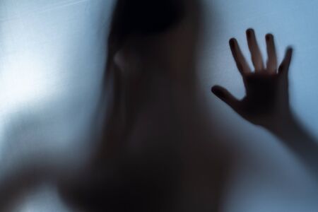 Blurred Woman's hand shadow asking for help. Horror and domestic violence conceptの写真素材