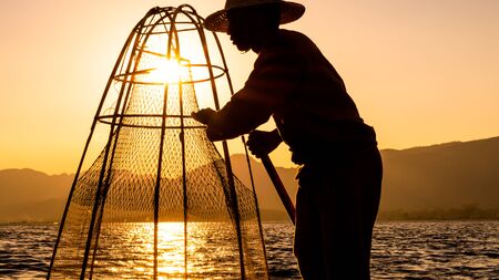 Fishermen working with a net during a golden summer afternoon in Inle Lake, Myanmarの写真素材