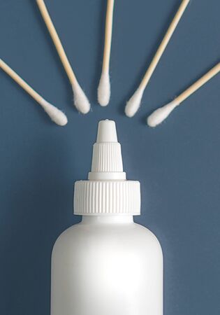 White bottle for mock up of pet ear cleaner product with blurred bamboo cotton swabs on a blue...
