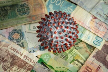 A ball painted like a SARS-CoV-2 virion on the middle of many banknotes from different countries