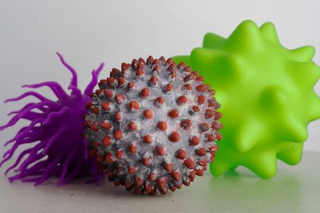 Two ball toys as a representation of virus or bacterias and one as a symbol of a SARS-CoV-2 virionの写真素材