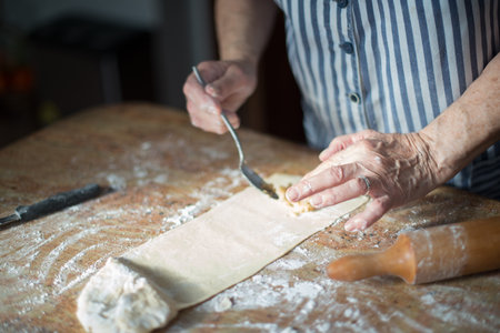 Typical Asturian Christmas dessert. Aged woman's hands putting the nut filling on the homemade dough...
