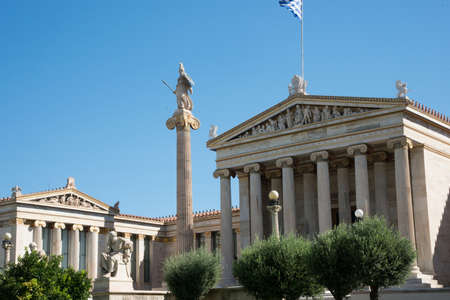 Academy of Athens neoclassical building with statues, flag and blue skyの写真素材