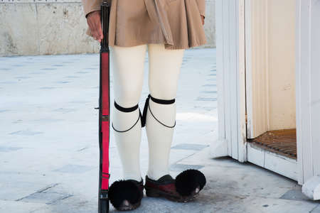 Greek guard with typical uniform at Syntagma Square in front of Hellenic Parliament. He is wearing his Gtsarouchia, the traditional shoes of Evzones which are red with a small tuft in frontの写真素材