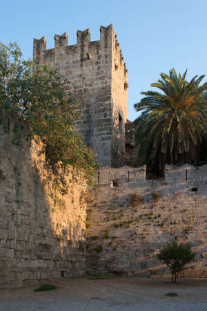 Rhodes town fortifications: old stone tower and palmtree at sunset. Beautiful landmark. Dodecanese, Greece.の写真素材