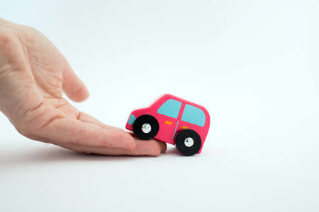 Close up of a caucasian beautiful hand helping a pink car to go up.White background. Conceptual for help.の写真素材