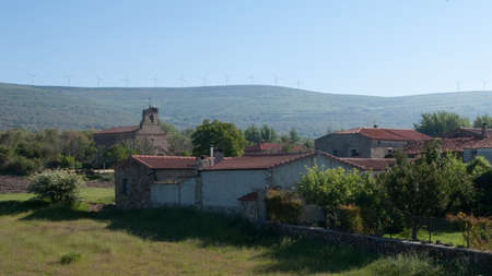 Beautiful spanish village with stone houses. Wind turbines on the hills behind as backgroundの写真素材