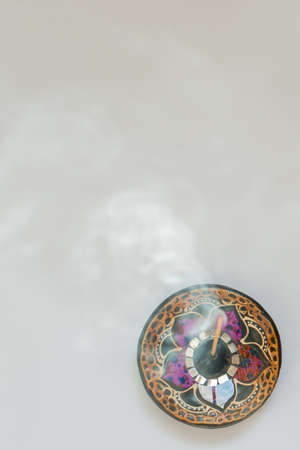 Colorful incense stick holder seen from above with swirling smoke.の写真素材