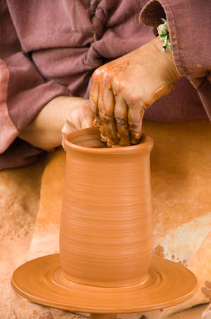 Sculpting a clay vase: working with her hands on a potters wheelの写真素材