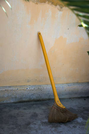 Traditional asian broom with a yellow stick close to a wall. Outdoors, no people. Vietnam, Asiaの写真素材