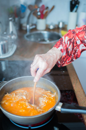 Senior woman cooking rice with chicken at home. Smoke aroundの写真素材