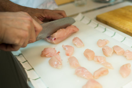 Unrecognizable man cutting chicken breast with japanese knife. Interior
