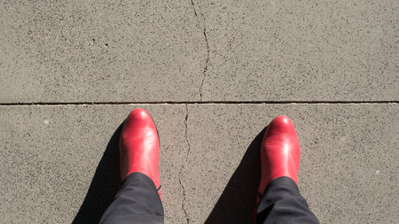 Woman wearing red boots, seen from above, about to cross a lineの写真素材
