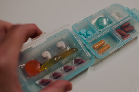 Colorful pills in a dispenser. Human hand opening