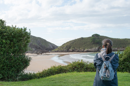 Unrecognizable woman looking to Barro beach with no people, in Llanes, Asturias. Seen from her backの写真素材