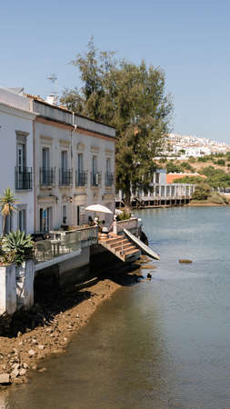 Tavira, Portugal; August 10, 2020: Old houses across the river next to the Roman bridge in Tavira, Portuguese Algarve.のeditorial素材