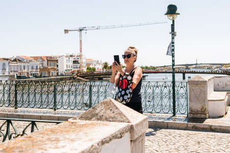 Tavira, Portugal; August 10, 2020: Tourist woman taking a photo on the street with her mobile while she is on vacation.のeditorial素材