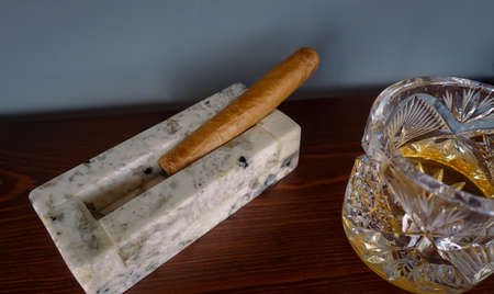 stone ashtray with cigars on a wooden tableの写真素材