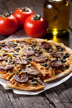 Homemade pizza with salami, cheese and black olives.の写真素材