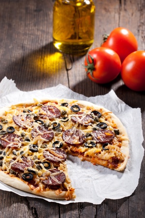 Homemade pizza with salami, cheese and black olives.の写真素材