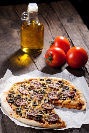 Homemade pizza with salami, cheese and black olives.の写真素材