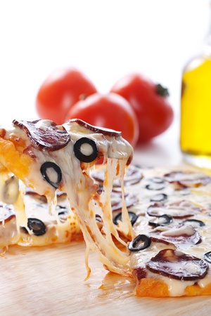 Slice of pizza with salami, black olives and melted cheese.の写真素材