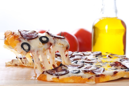 Slice of pizza with salami, black olives and melted cheese.の写真素材