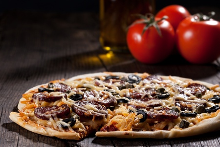 Homemade pizza with salami, cheese and black olives.の写真素材