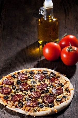 Homemade pizza with salami, cheese and black olives.の写真素材