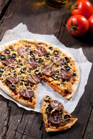 Homemade pizza with salami, cheese and black olives.の写真素材