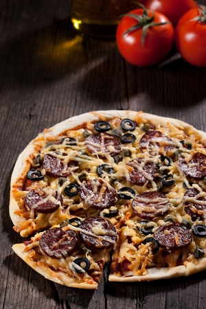 Homemade pizza with salami, cheese and black olives.の写真素材