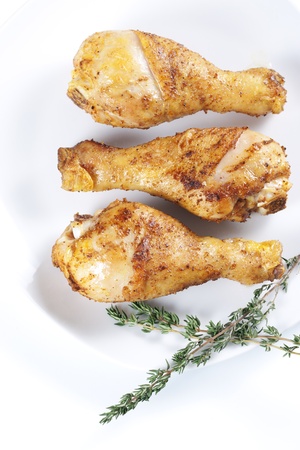 Roasted chicken legs with thyme on a plateの写真素材