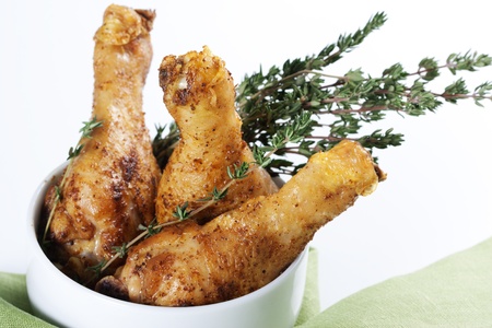 Roasted chicken legs with thyme in a bowlの写真素材
